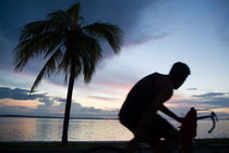 Man cycling along the waterfront at sunset by Sami Sarkis Photography