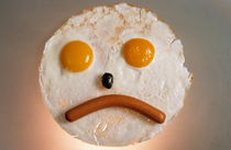 Fried breakfast of eggs and sausage made into a frowning face. by Sami Sarkis Photography