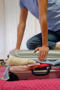 Woman closing overflowed suitcase by Sami Sarkis Photography