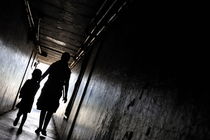 Mother and daughter walking in a dark corridor von Sami Sarkis Photography