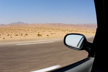 Side-view mirror of car speeding on desert highway von Sami Sarkis Photography