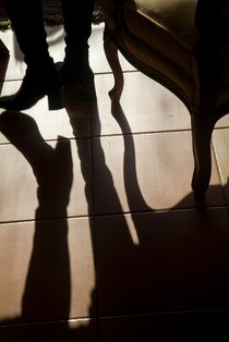 Shadow of woman's foot and furniture on floor by Sami Sarkis Photography