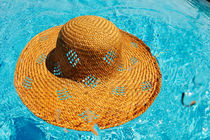 Straw hat floating on pool by Sami Sarkis Photography