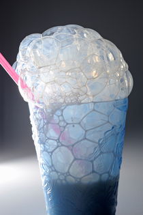 Milk bubbles out of a glass with straw by Sami Sarkis Photography