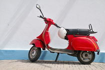 Red Vespa scooter by wall by Sami Sarkis Photography