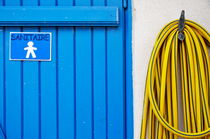 Men's closed bathroom door and hose by Sami Sarkis Photography