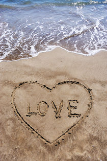 Heartshape drawn in sand on beach with Love word inside von Sami Sarkis Photography