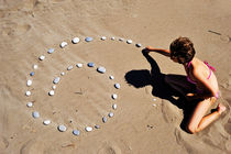 Girl on beach displaying pebbles in spiral shape von Sami Sarkis Photography