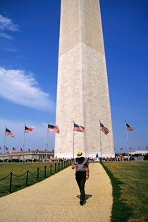 Man walking down a footpath with the Washington Monument in the background by Sami Sarkis Photography
