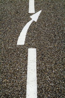 Painted white arrow sign in the dividing line on the road. by Sami Sarkis Photography