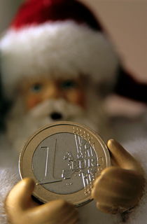 Santa Claus doll holding out a euro coin. by Sami Sarkis Photography