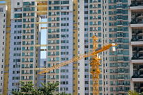 Construction crane in front of the facade of a large apartment building by Sami Sarkis Photography