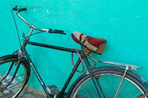 Old black bike parked against a green wall by Sami Sarkis Photography