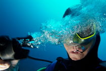 One scuba diver pulls the breathing regulator out of his mouth while still underwater by Sami Sarkis Photography