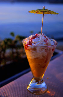 Peach ice cream sundae served with a cocktail umbrella in a glass. von Sami Sarkis Photography