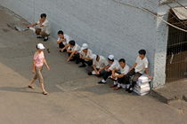 Restaurant workers having a break outside as a woman walks past by Sami Sarkis Photography