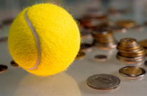 Tennis ball next to numerous piles of coins. von Sami Sarkis Photography