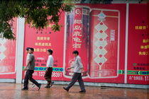 Men walking past a huge advertisement while walking down the street together in Beijing by Sami Sarkis Photography