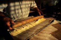 Baker rolling pastry with a rolling pin inside a bakery von Sami Sarkis Photography