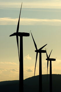 Silhouetted wind turbines against a cloudy sky by Sami Sarkis Photography