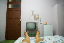 Man's legs on a bed in front of an old TV at a guesthouse von Sami Sarkis Photography
