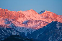 Snowy mountain range with a rosy hue at sunset. von Sami Sarkis Photography