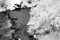 Snow-covered rocks beside a mountain stream in the French Alps von Sami Sarkis Photography