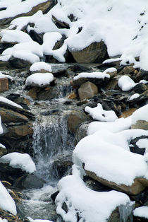 Snow-covered rocks beside a mountain stream in the French Alps von Sami Sarkis Photography