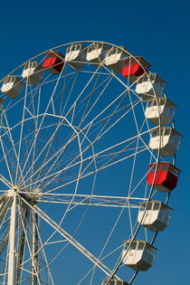 Red and white empty carriages on a ferris wheel at an amusement park. by Sami Sarkis Photography