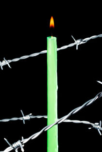 Lit candle surrounded by barbed wire. von Sami Sarkis Photography