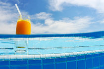 Glass of orange juice on pool ledge von Sami Sarkis Photography